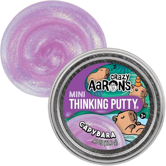 Swirl of shimmering purple putty next to a silver tin featuring cute cartoon capybaras on a purple label.