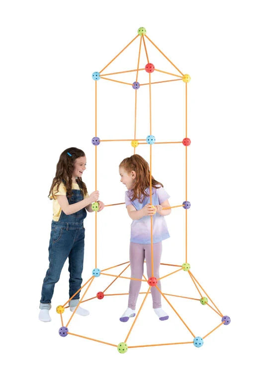 Two kids building a tall rocket-shaped structure using orange rods and colorful connector balls.