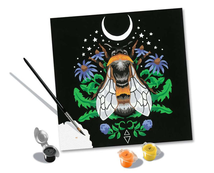 Stylized bee paint-by-number kit featuring a moon and flowers, including a paintbrush and three paint pots.