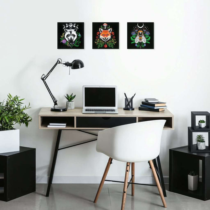 Square black canvas featuring a colorful bee and floral illustration, hung above a desk as part of a three-piece art set.