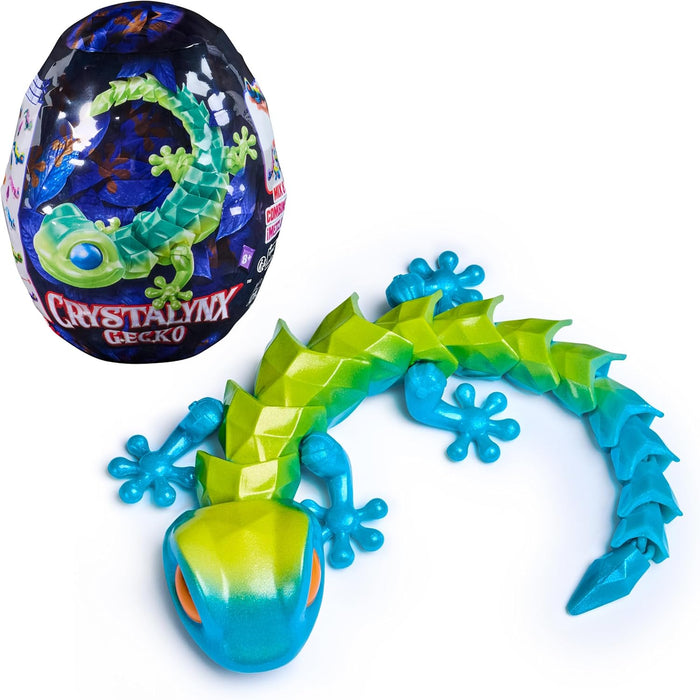 Articulated green and blue faceted toy gecko with orange eyes next to its illustrated egg packaging.