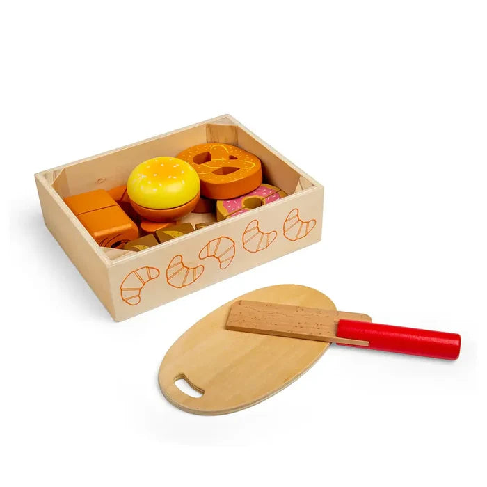 Wooden crate of toy pastries, pretzel, and burger with a wooden cutting board and red-handled play knife.