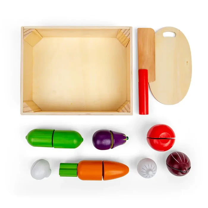Wooden crate, cutting board, and red-handled knife with sliced play vegetables like a carrot, tomato, and eggplant.