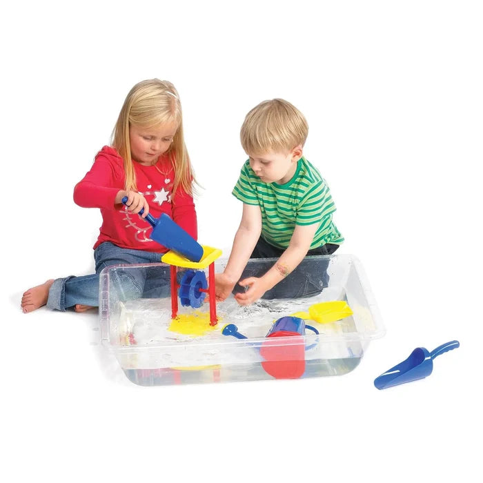 Two children playing with colorful toys in a shallow, clear rectangular plastic tray filled with water.