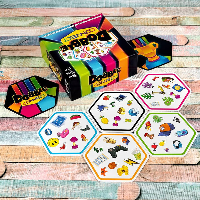 Rainbow-striped Dobble Connect box and hexagonal cards with colorful symbols on a rustic wooden surface.