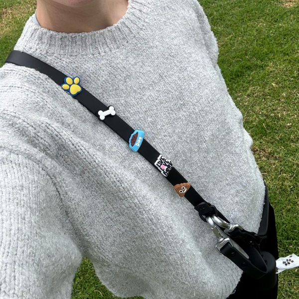 Black Walkieez dog poop bag holder and dispenser with a compact design, attached to a leash clip for easy access during walks.