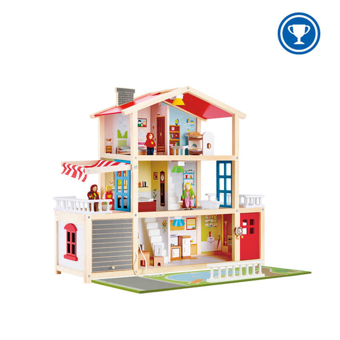 Three-story wooden dollhouse with red roof, furnished rooms, figures, rolling garage door, and garden play mat.