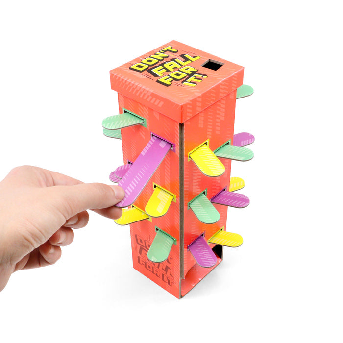 Orange rectangular tower game with colorful green, yellow, and pink cardboard tabs. A hand pulls one pink tab out.