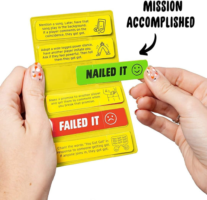 Yellow mission card with tasks, held by hands sliding out a green Nailed It tab. Red Failed It tab below.