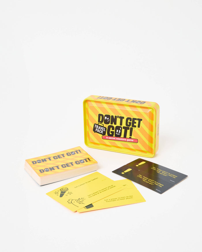 Yellow and orange striped tin box with suitcase logo, stack of cards, and mission cards on a white background.