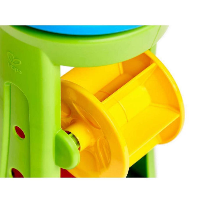 Close-up of a lime green plastic toy with a yellow paddle wheel and the Hape logo embossed on the side.