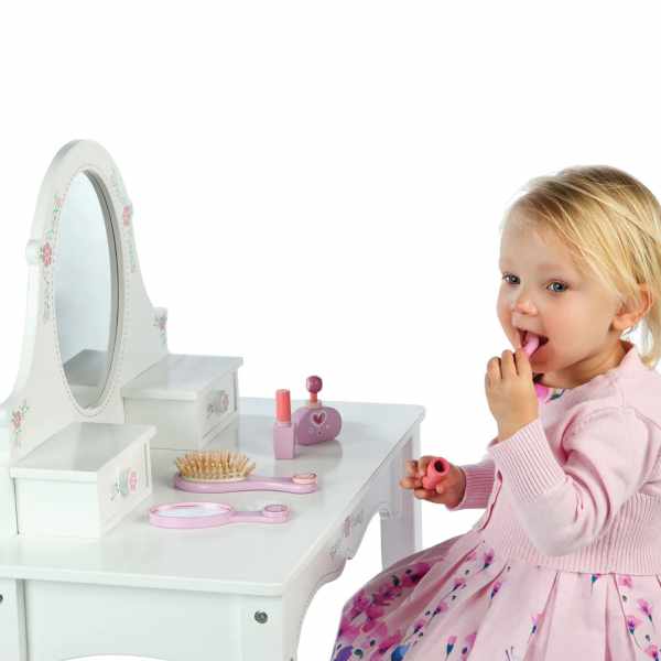 Toddler girl playing at a white wooden toy vanity with an oval mirror and pink pretend makeup accessories.