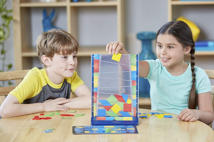 Two children drop colorful geometric shapes into a tall, clear vertical tower while playing the Drop It game.