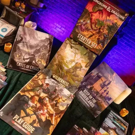 D&D Starter Set booklets with fantasy art on a green surface, lit by atmospheric purple and warm candlelight.