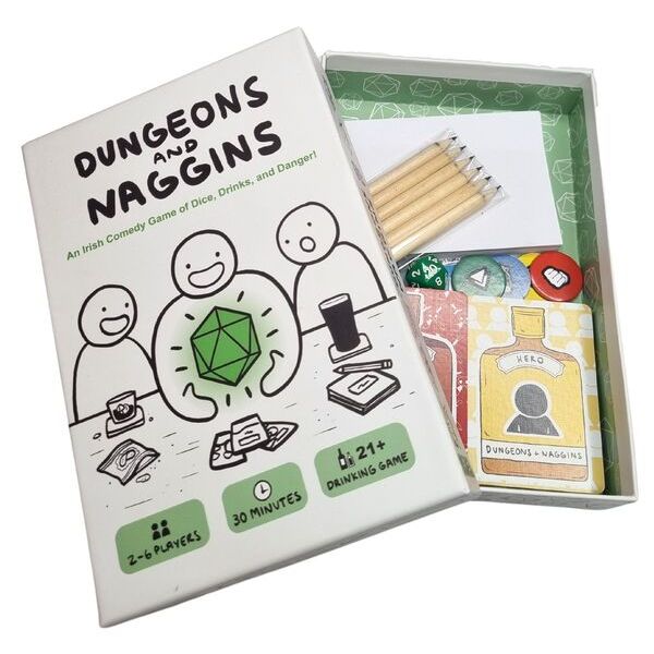 Open Dungeons and Naggins box with cartoon art, pencils, a green d20 die, and cards featuring whiskey bottle art.