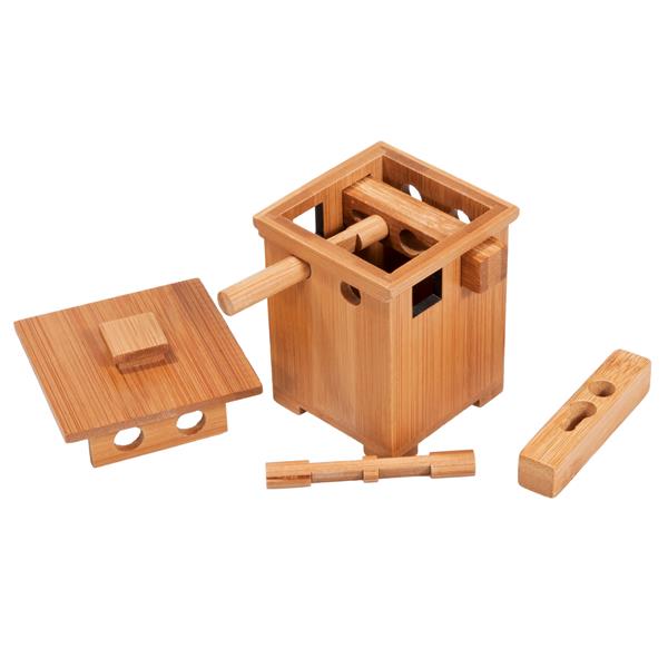 Disassembled light wood puzzle box with a square lid, round pegs, and interlocking blocks on a white background.