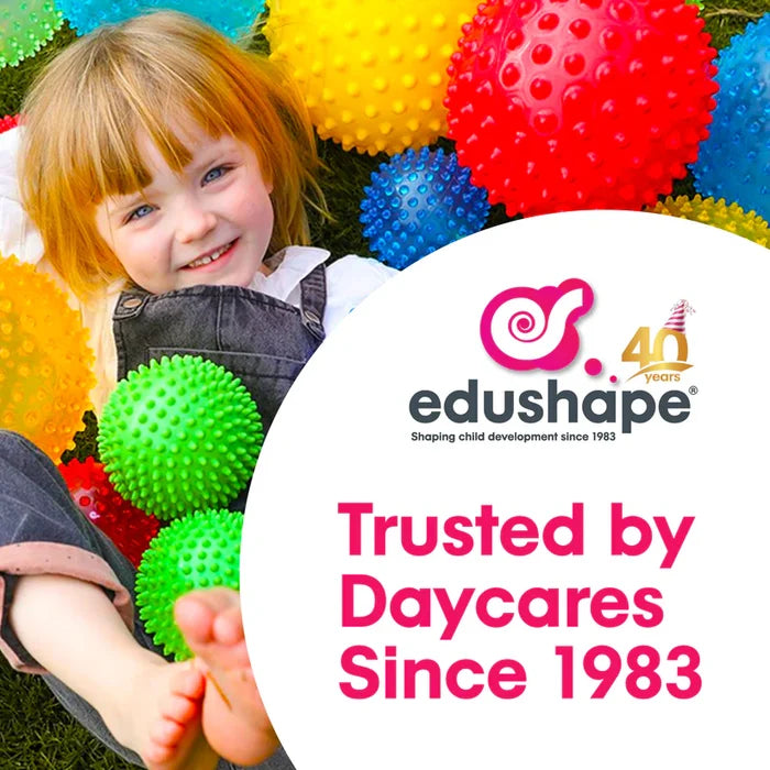 Smiling girl lying in grass surrounded by bright, nubby sensory balls and the Edushape 40th anniversary logo.