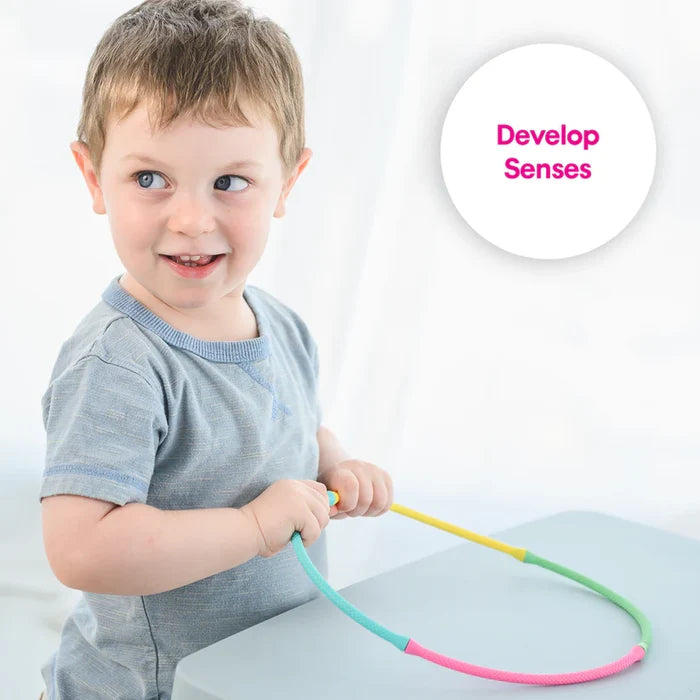 Toddler joining colorful, textured flexible rods. White circle with pink text says Develop Senses.