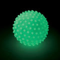 Neon green glow-in-the-dark ball with a bumpy sensory texture, shown glowing against a dark background.