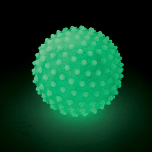 Neon green glow-in-the-dark ball with a bumpy sensory texture, shown glowing against a dark background.