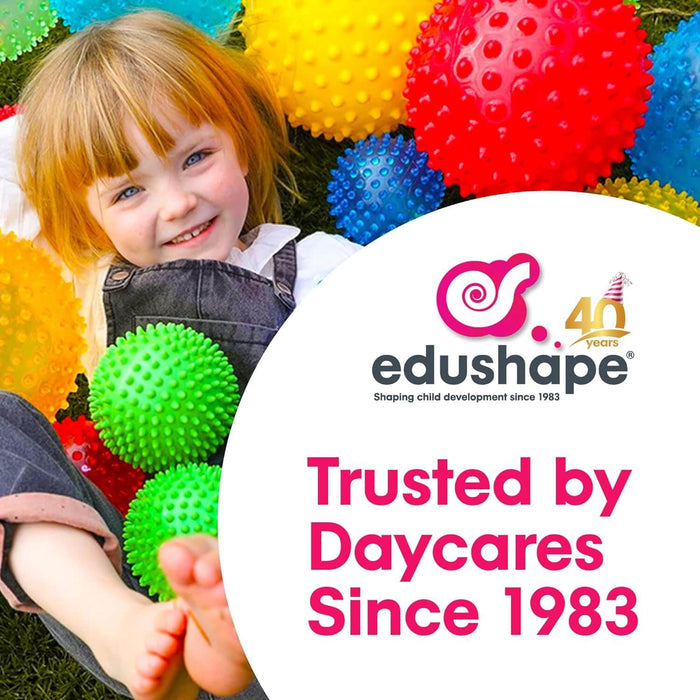 Smiling girl lies on grass among colorful, knobby sensory balls. Text: Trusted by Daycares Since 1983.
