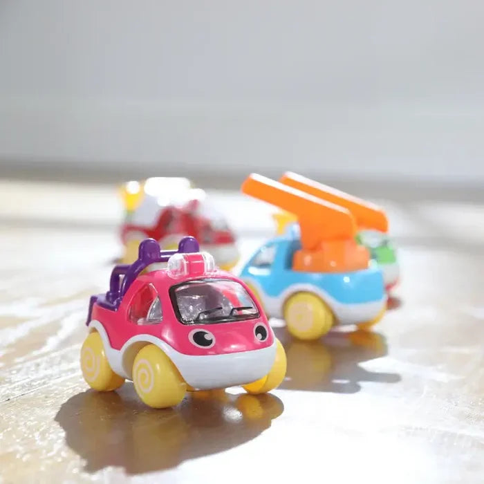 Three colorful, rounded toy cars in pink, blue, and red with chunky yellow wheels on a wooden floor.