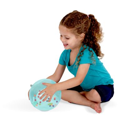 A young girl holds a teal translucent soft ball filled with small, multi-colored rainbow beads.