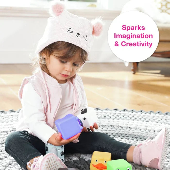 Toddler playing on a rug with soft animal-shaped blocks like a yellow duck, purple cube, and white spotted block.
