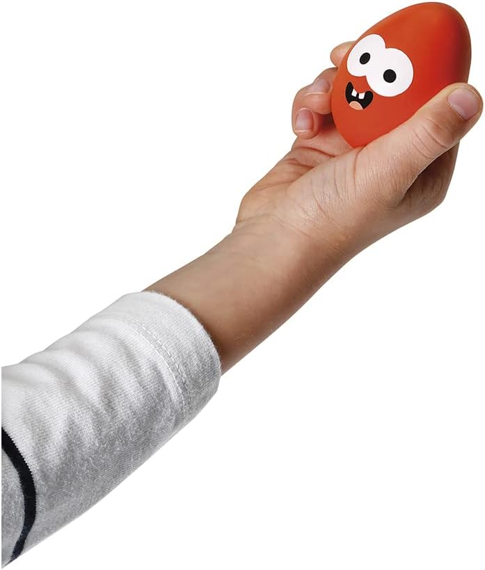 Child's hand holding an orange egg toy with a smiling cartoon face.