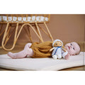 Soft plush doll in a blue and white striped hooded outfit lying next to a baby on a white padded mat.