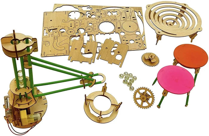 Unassembled laser-cut wood sheets, gears, green rods, motor, clear marbles, and orange and pink discs on white.