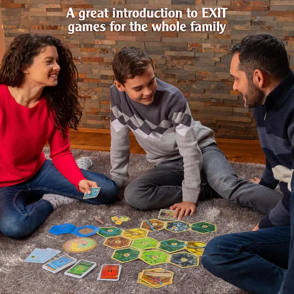 A family plays a board game with hexagonal tiles and cards on a grey carpet against a stone wall background.