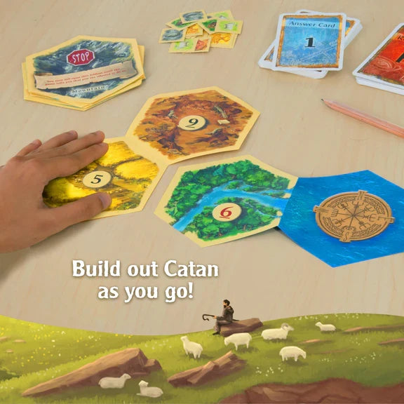 Hand placing numbered hexagonal terrain tiles on a table with puzzle cards, a pencil, and a landscape with sheep.