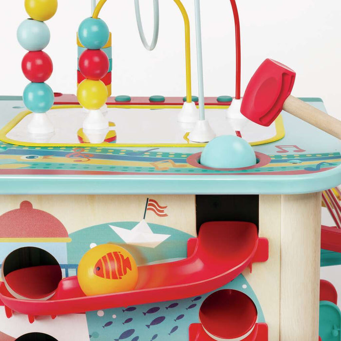Wooden activity cube with a bead maze, red mallet, and yellow fish ball rolling down a red slide.