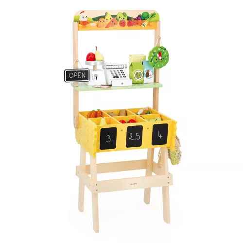 Light wood toy market stall featuring yellow bins with pretend produce, a play scale, cash register, and clock.