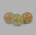 Three translucent rubbery spheres filled with colorful miniature toy food like burgers, tacos, and fries.