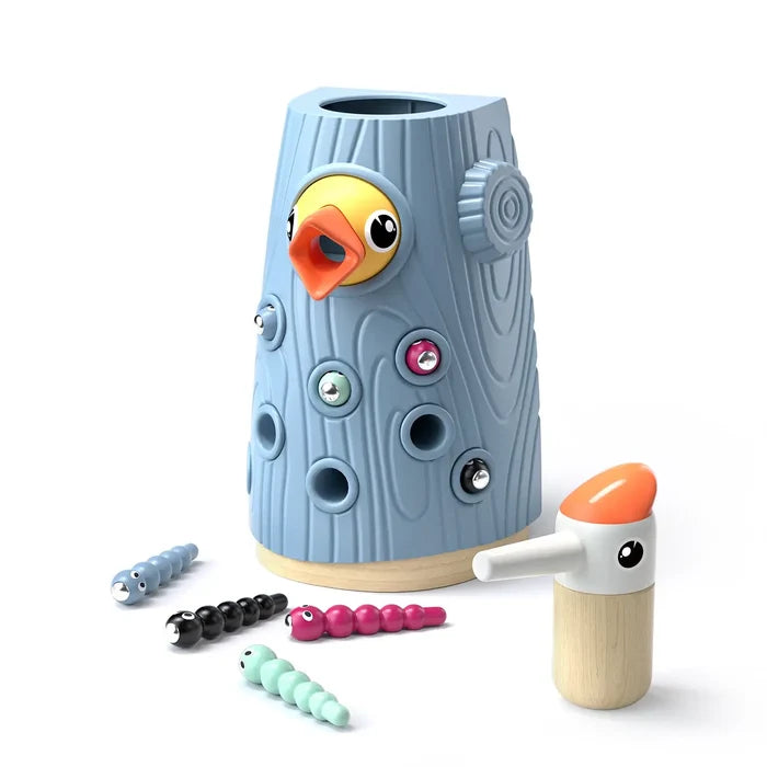Blue woodgrain toy tree stump with yellow bird, magnetic caterpillars, and woodpecker tool on white background.