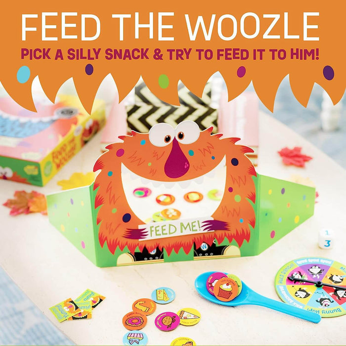 Orange monster cutout with an open mouth, colorful snack tokens, a blue spoon, and a game spinner.