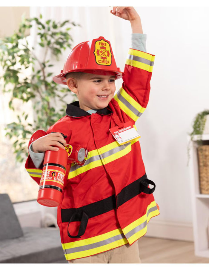 Child wearing a red fire chief costume with yellow stripes and helmet, holding a small toy fire extinguisher.