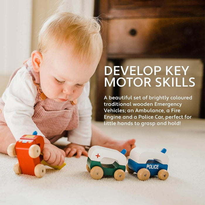 Baby playing with a red wooden fire engine, green ambulance, and blue police car with natural wood wheels.