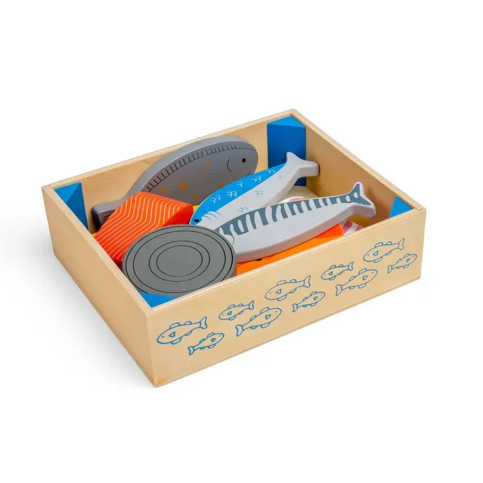 Wooden crate with blue fish patterns containing colorful toy fish, an orange salmon fillet, and a round tin piece.