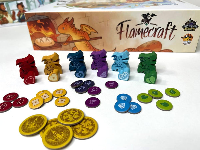 Colorful dragon meeples and tokens for bread, crystals, and meat in front of a Flamecraft board game box.