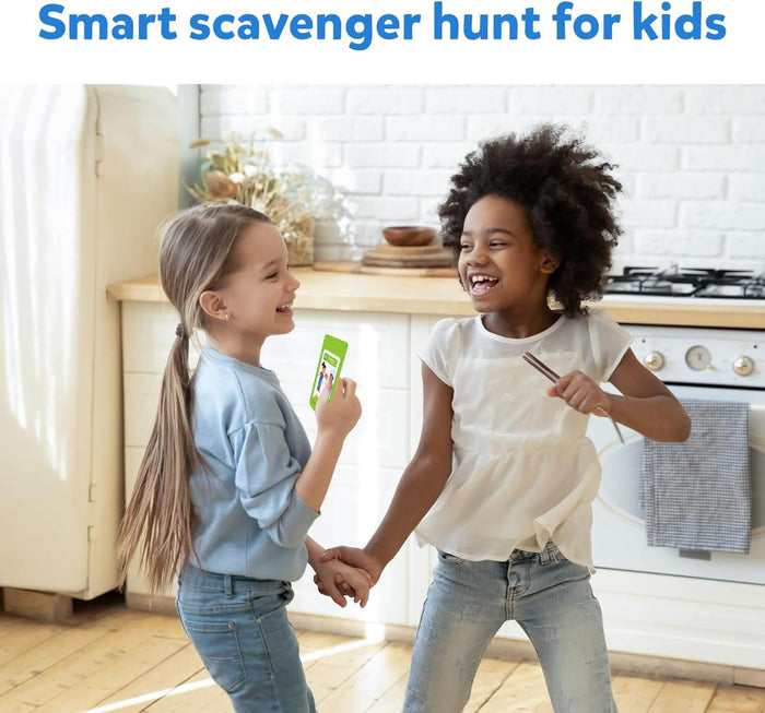 Two young girls laugh and play together in a bright kitchen, one holding a green game card and the other a whisk.