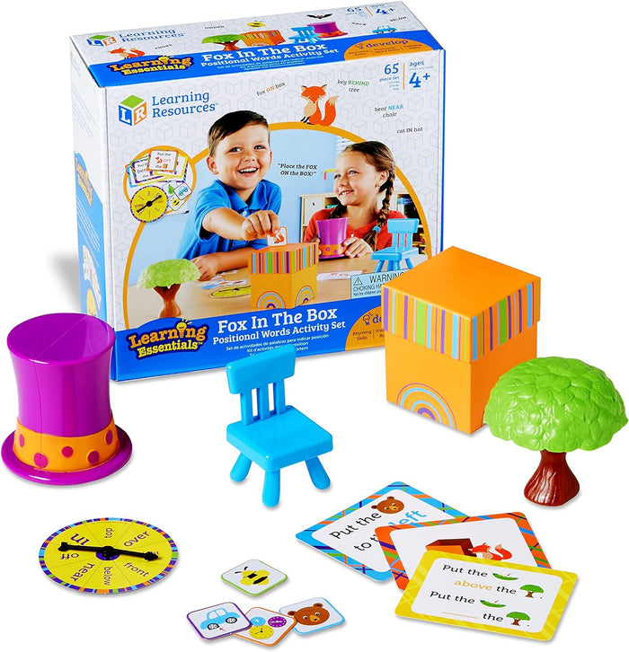 Fox In The Box activity set featuring a purple hat, blue chair, orange box, tree, spinner, and cards with packaging.