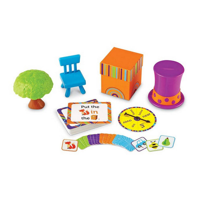 Educational toy set with a green tree, blue chair, patterned orange box, purple hat, game cards, and a spinner.