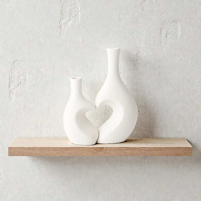 Pair of white ceramic vases with heart-shaped designs from Nest & Stem Homewares, ideal for home decor and floral arrangements.