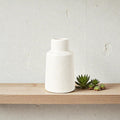Small white ceramic vase with speckle pattern by Nest & Stem Homewares, ideal for holding flowers or decorative arrangements.