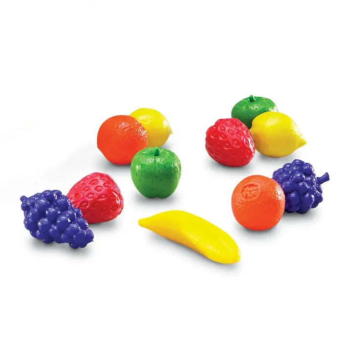 Small, textured plastic fruit counters in bright colors including purple grapes, red strawberries, and green apples.