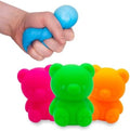Hand squeezing a blue squishy bear toy next to three neon bears in pink, green, and orange.
