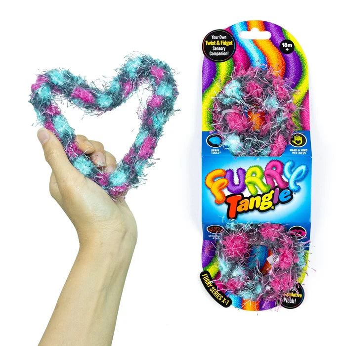 Hand holding a heart-shaped pink and teal fuzzy twist toy next to its vibrant rainbow retail packaging.